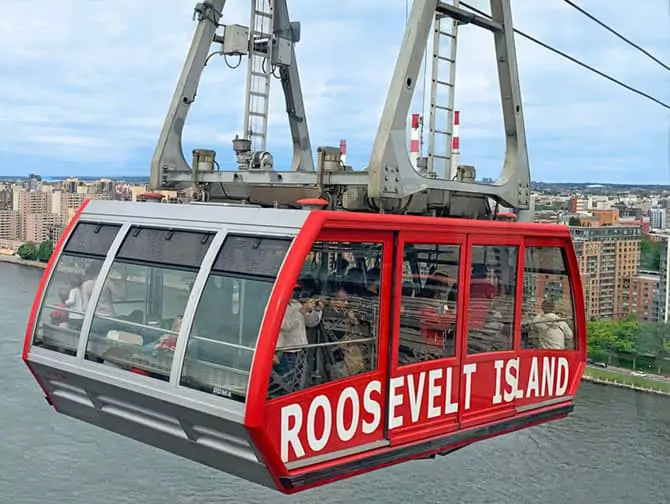 Red Roosevelt Island Tram cabin crossing the East River alongside the Queensboro Bridge
