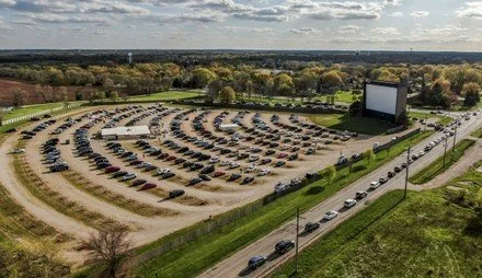 Cars parked at a drive-in movie theater at dusk