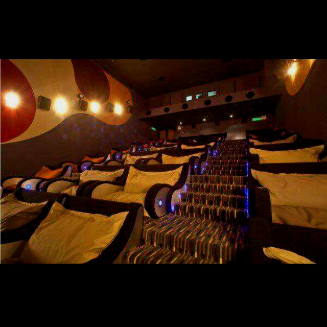 Couple sitting closely in a movie theater love seat with the armrest raised