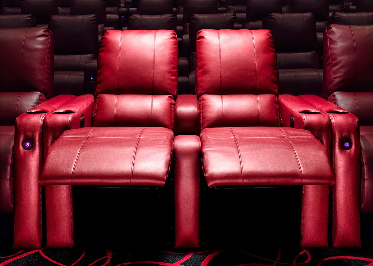 Two people sitting in a boutique movie theater cuddle pod