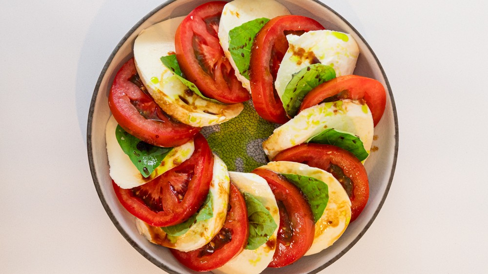 Close up of a freshly prepared Caprese salad showing the texture of the tomatoes and basil
