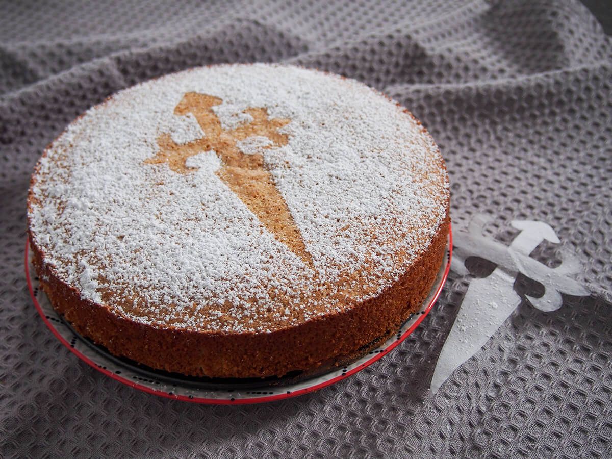 A slice of Tarta de Santiago showing the dense, moist almond interior