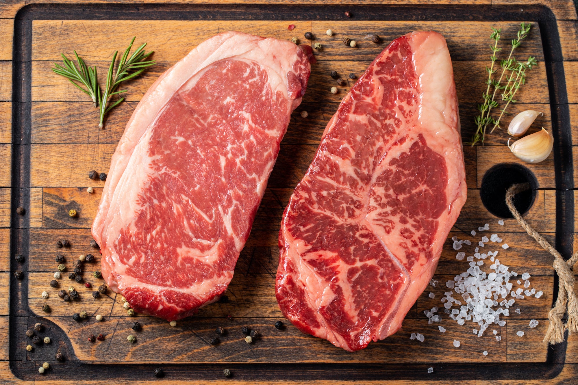 Raw Ribeye and New York Strip side by side showing marbling and fat cap