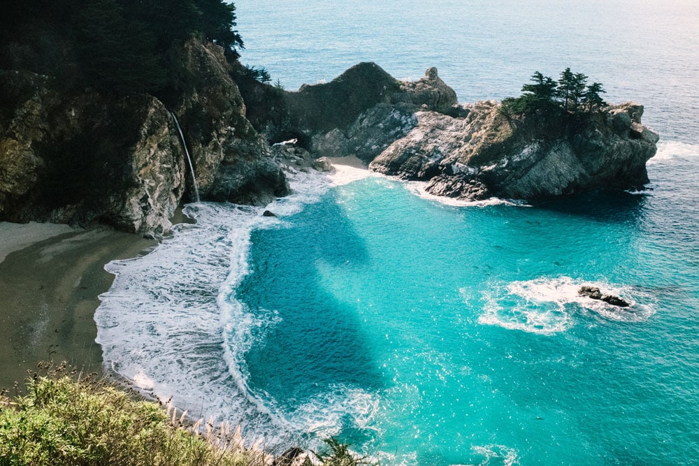 A scenic coastal view with rugged cliffs and blue water, representing a cool summer destination